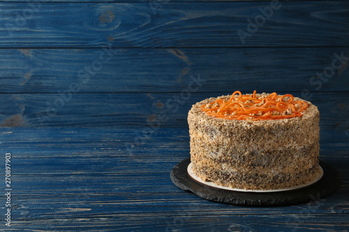 Dish with delicious carrot cake on blue wooden background. Space for text