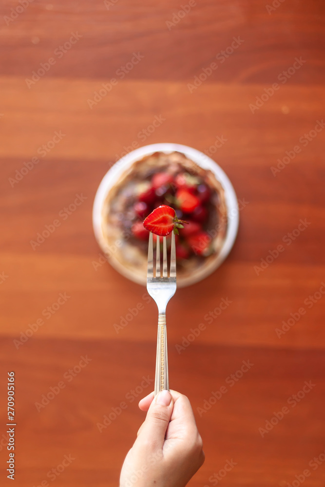 A young woman holding a fork with a strawberries