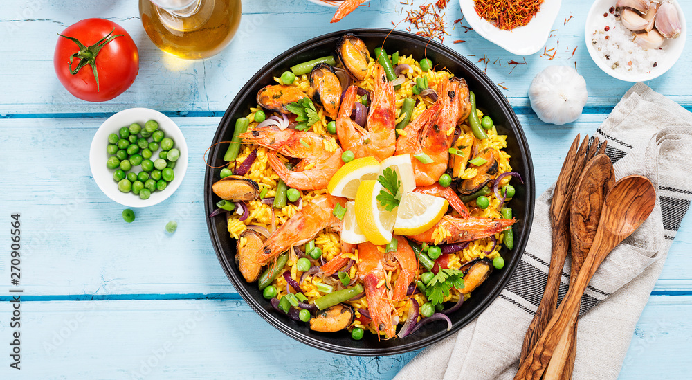 Traditional spanish seafood paella in the fry pan on a blue wooden table, top view. Traditional spanish seafood paella in the fry pan on a blue wooden table, top view.