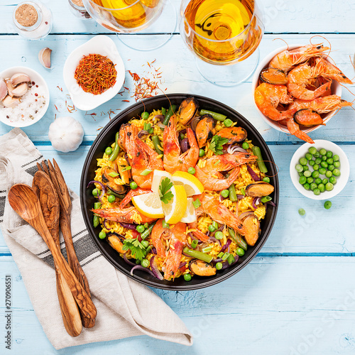 Traditional spanish seafood paella in the fry pan on a blue wooden  table, top view.