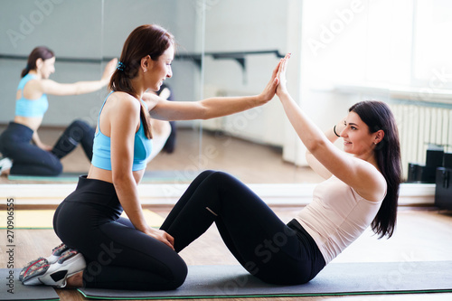 Personal trainer, teamwork, workout, perfect shape. Fit sporty woman doing sit-ups with fitness instructor support