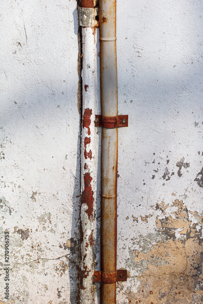 Rusty pipe hanging on the old house wall Rusty pipe hanging on the old house wall