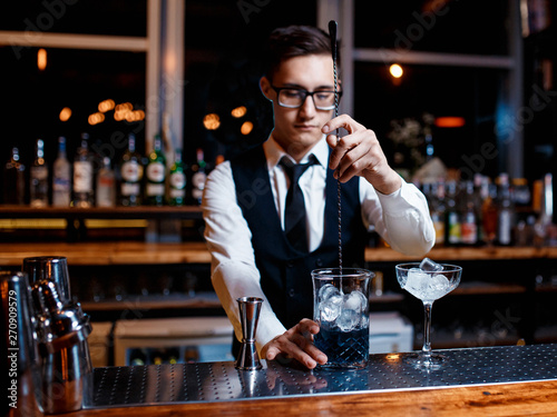 The bartender prepares a cool blue lagoon cocktail. Barman at work