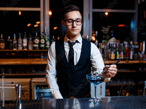 The bartender prepares a cool blue lagoon cocktail. Barman at work