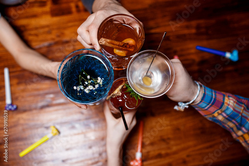 friends clinking by glasses with various alcoholic cocktails at table,close up top view