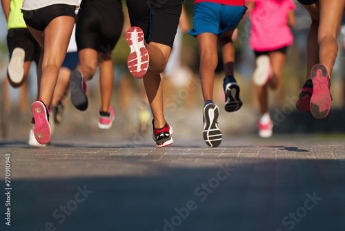 Fototapeta Naklejka Na Ścianę i Meble -  Running children, young athletes run in a kids run race,running on city road detail on legs,running in the light of morning