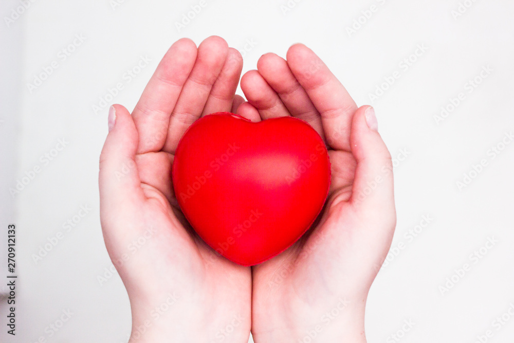 Heart in the hands of a man close up. Close up on female hands giving a red heart as a heart donor. Sign of compassion and health. Heart in the hands of a man close up. Close up on female hands giving a red heart as a heart donor. Sign of compassion and health.