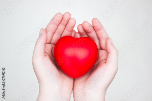 Heart in the hands of a man close up. Close up on female hands giving a red heart as a heart donor. Sign of compassion and health.