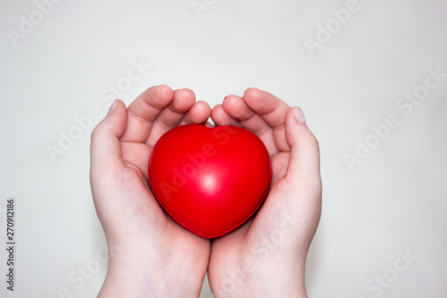 Fototapeta Naklejka Na Ścianę i Meble -  Heart in the hands of a man close up. Close up on female hands giving a red heart as a heart donor. Sign of compassion and health.
