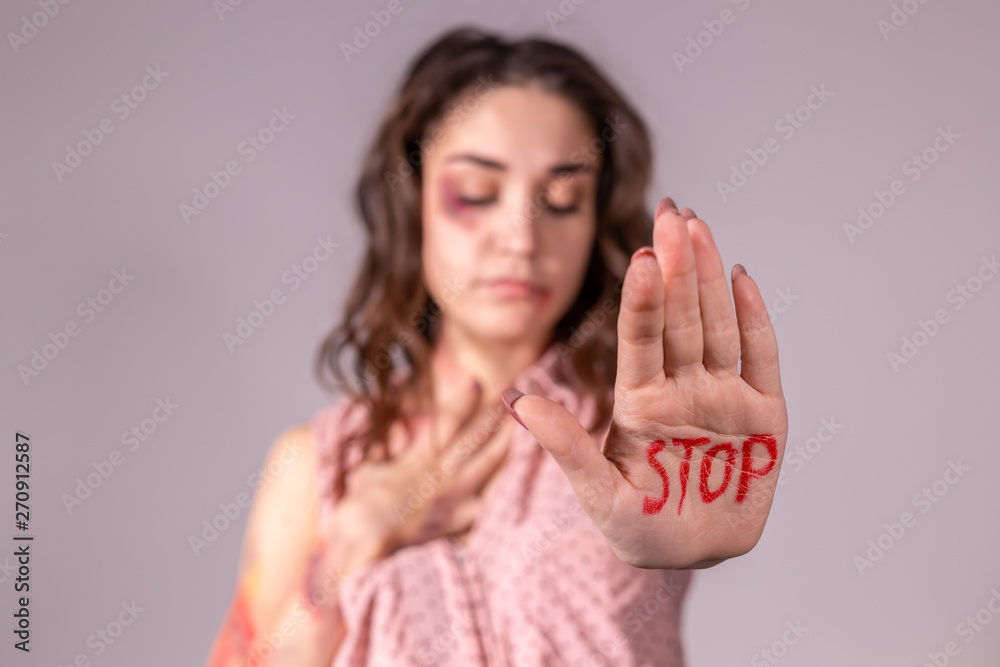 Domestic violence, protesting and people concept - brunette woman expressing denial with STOP on her hand on grey room Domestic violence, protesting and people concept - brunette woman expressing denial with STOP on her hand on grey room