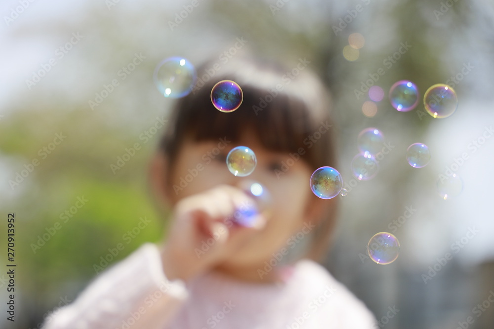 シャボン玉で遊ぶ幼児(4歳児)と青空