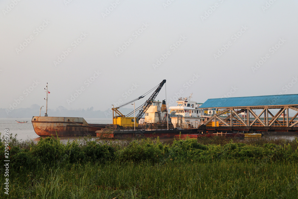 Fototapeta premium Crane on the ship with other ship moored at the harbor in river.