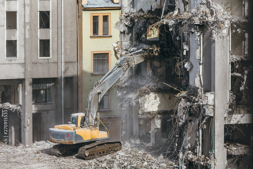 Photo of destroyed building, protruding reinforcement. Demolition of a building, house ruins, reconstruction, bricks and metal. Dismantling of structure.Heavy machinery, bulldozer, excavator-destroyer