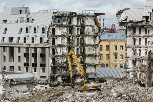 Photo of building demolition excavator. Destruction of a house, ruins, reconstruction, bricks and metal, heavy machinery, construction equipment, hydraulic excavator, bulldozer, construction site.