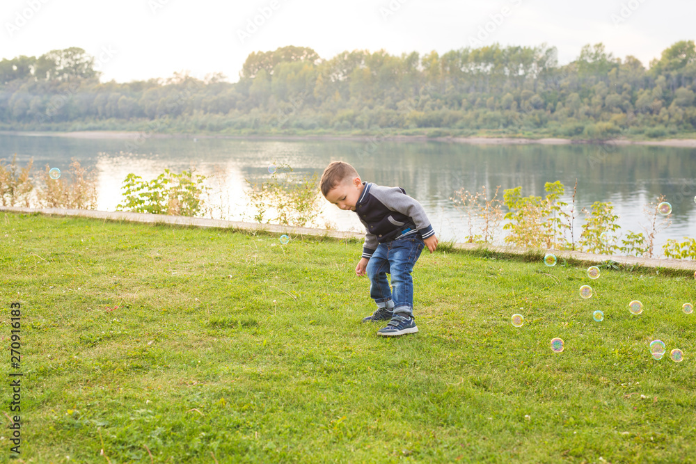 Chilhood, people concept - young boy playing with soap bubbles Chilhood, people concept - young boy playing with soap bubbles