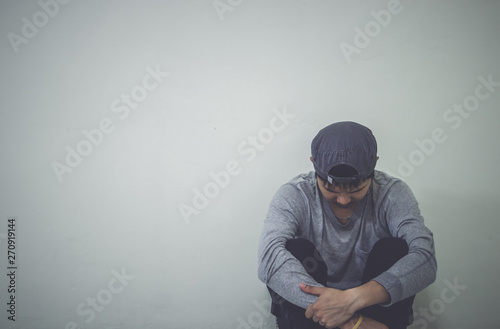 Depressed man sitting on floor in an empty room , This is major depressive disorder.