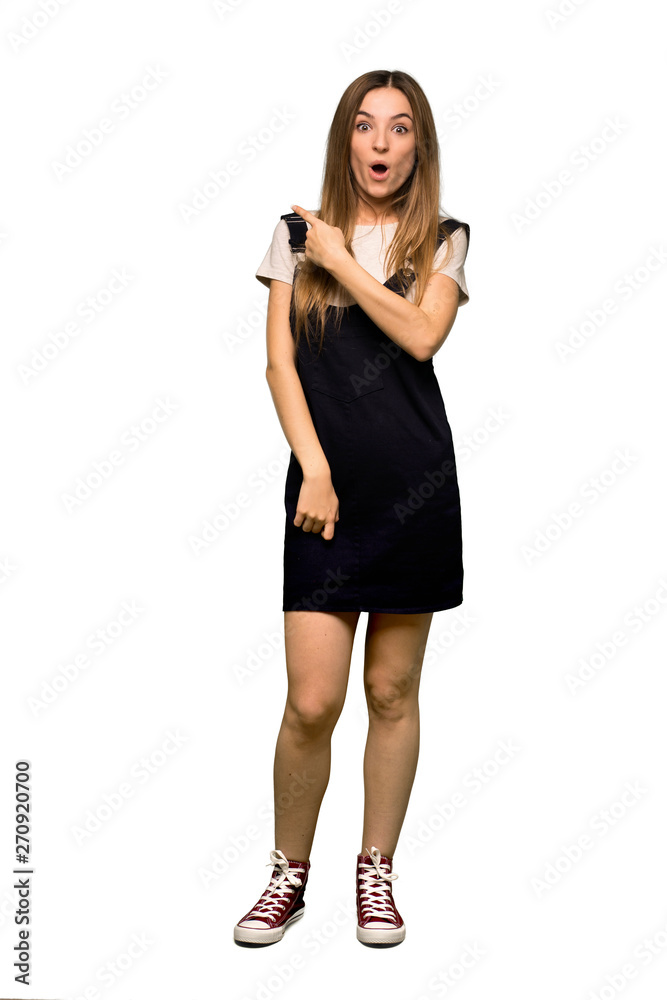 Full body Young pretty woman surprised and pointing side on isolated background Full body Young pretty woman surprised and pointing side on isolated background