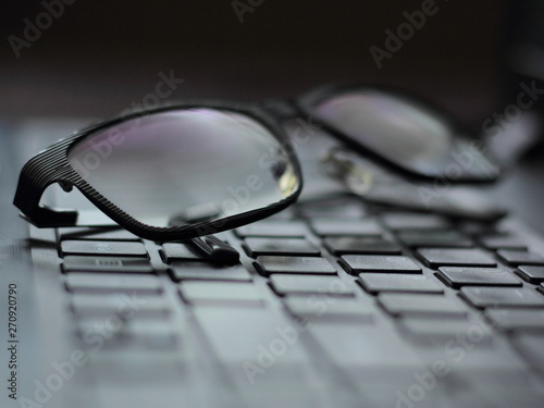 Closeup of framed glasses on a laptop. Dark eyewear on a black keyboard.