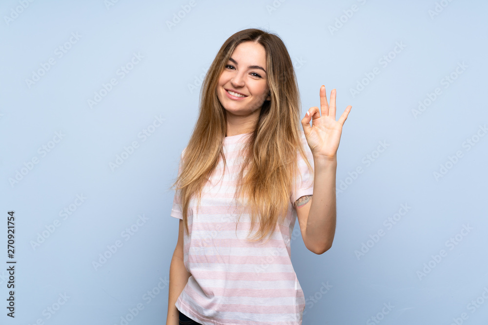 Young woman over isolated blue background showing ok sign with fingers Young woman over isolated blue background showing ok sign with fingers