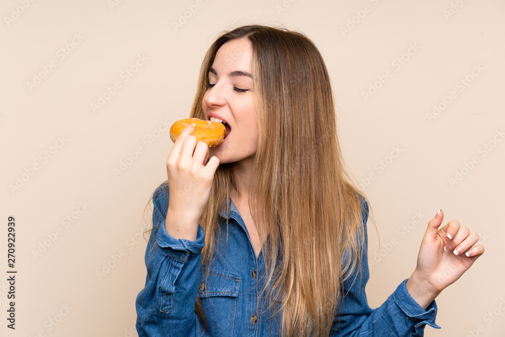 Young woman holding a donut over isolated background Young woman holding a donut over isolated background