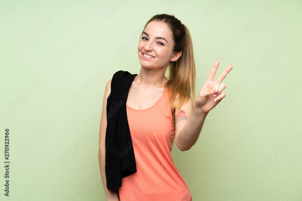 Young sport woman over green wall smiling and showing victory sign Young sport woman over green wall smiling and showing victory sign