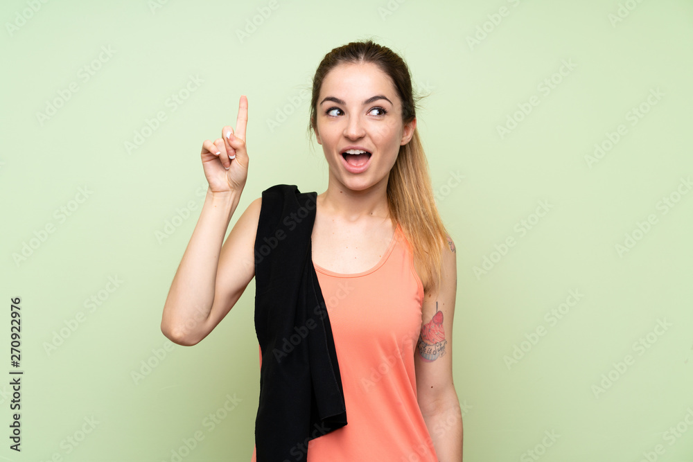 Young sport woman over green wall intending to realizes the solution while lifting a finger up Young sport woman over green wall intending to realizes the solution while lifting a finger up