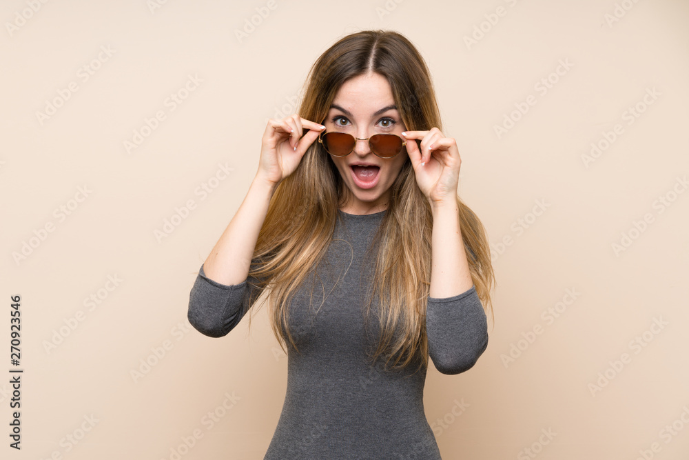 Young woman over isolated background with glasses and surprised Young woman over isolated background with glasses and surprised