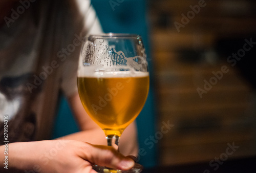 man's hand holds a glass of beer in bar