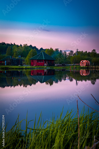 Small village red house with smoke reflects in clerly still water at evening photo