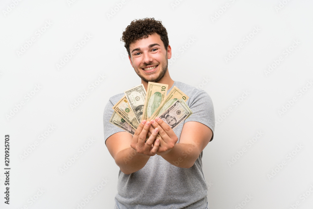 Man with curly hair over isolated wall taking a lot of money Man with curly hair over isolated wall taking a lot of money