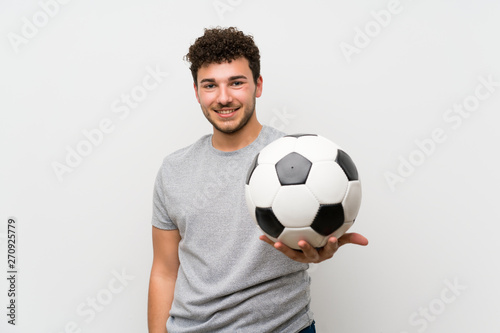 Man with curly hair over isolated wall holding a soccer ball © luismolinero