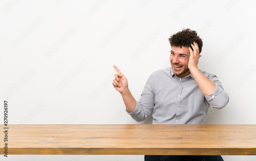 Young man with a table surprised and pointing finger to the side Young man with a table surprised and pointing finger to the side
