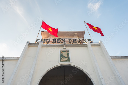 Papier peint Ben Thanh Market (built in 1912-1914), the facade and the arch of the central entrance and two swaying Vietnamese flags