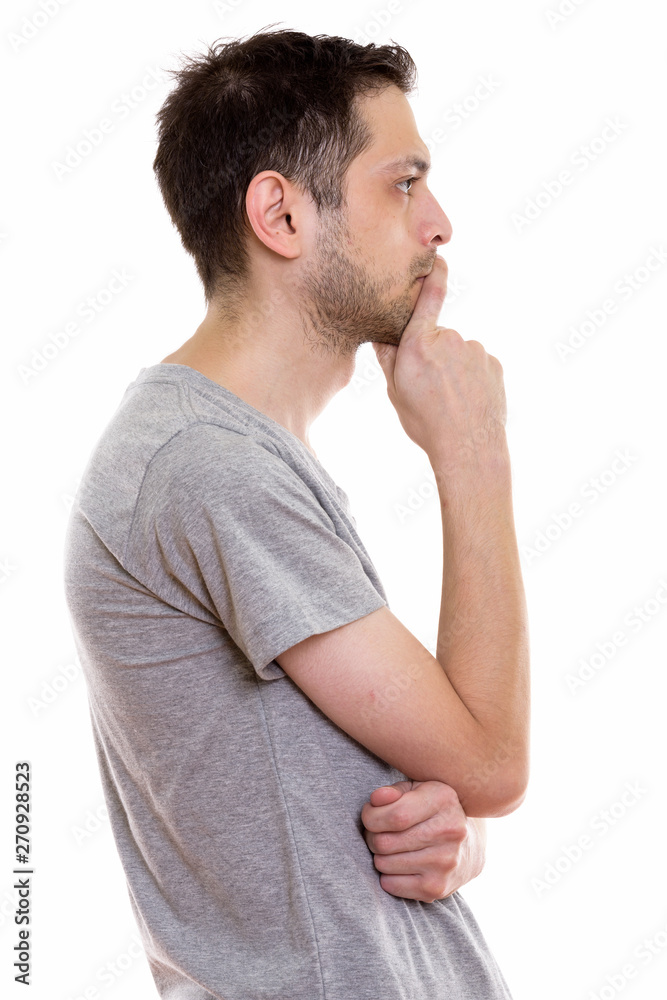 Profile view portrait of young man standing and thinking Profile view portrait of young man standing and thinking