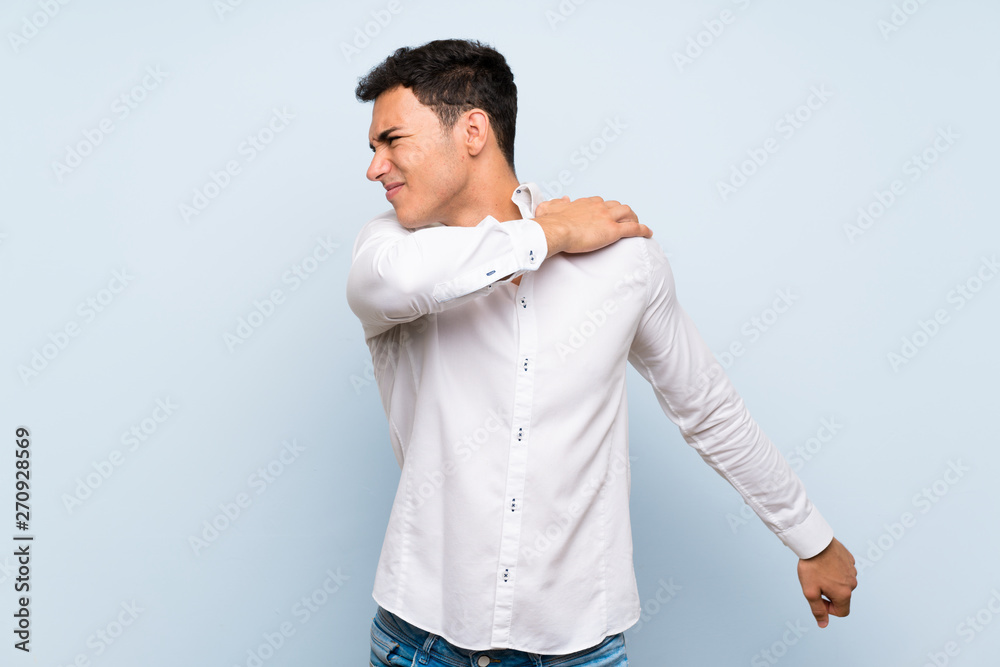 Handsome man over blue wall suffering from pain in shoulder for having made an effort Handsome man over blue wall suffering from pain in shoulder for having made an effort