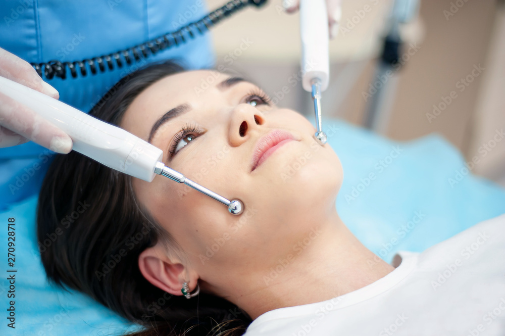 cosmetologist with a patient during facial procedures in a modern cosmetological and aesthetic clinic. A patient receives an electric facial massage. Skin rejuvenation and wrinkle smoothing. cosmetologist with a patient during facial procedures in a modern cosmetological and aesthetic clinic. A patient receives an electric facial massage. Skin rejuvenation and wrinkle smoothing.