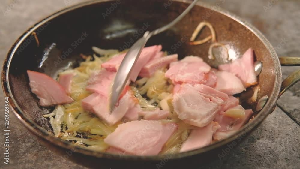 Food cooking process. Meal ingredient preparation. Chef stirring ham bacon with sliced squid and onions in frying pan. Food cooking process. Meal ingredient preparation. Chef stirring ham bacon with sliced squid and onions in frying pan.