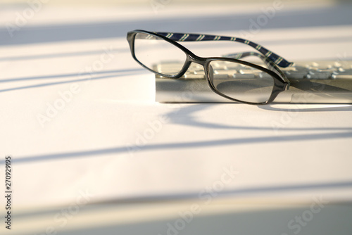 Business concept: keyboard and reading glasses on white background