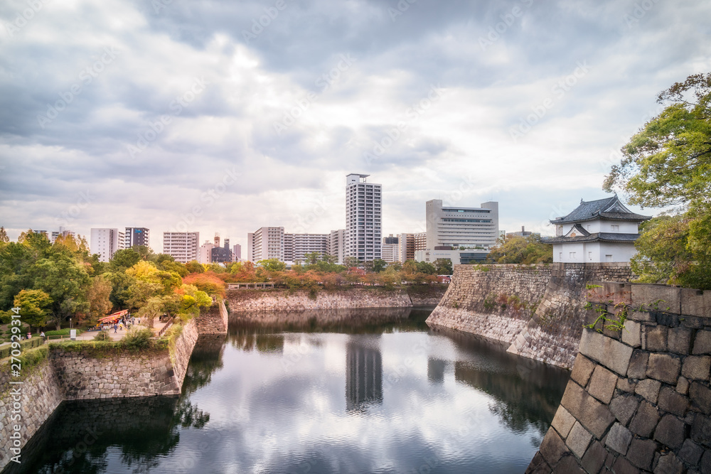 Reflections in the water at Osaka Castle Park Moat and outerwall with Osaka cityscape in the distance in Japan.