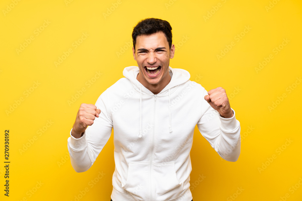 Lucky handsome man over isolated yellow wall Lucky handsome man over isolated yellow wall