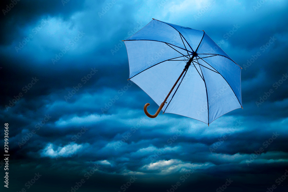 blauer Regenschirn fliegt beim Sturm davon