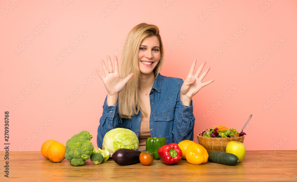 Young blonde woman with many vegetables counting nine with fingers Young blonde woman with many vegetables counting nine with fingers