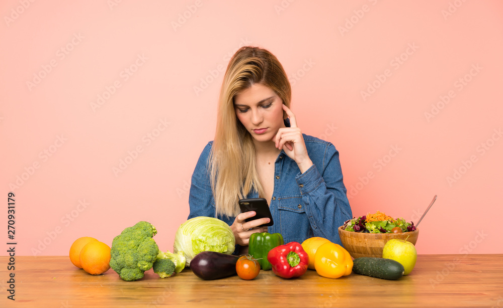 Young blonde woman with many vegetables thinking and sending a message Young blonde woman with many vegetables thinking and sending a message