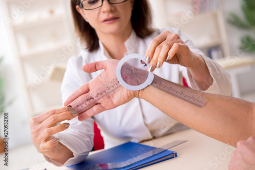 Obraz na plátne Female doctor checking patient's joint flexibility with goniometer