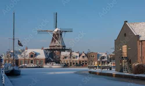 Traditional windmill in winter Meppel Drenthe Netherlands. Frozen canal Sluisgracht. Stoombootkade. photo