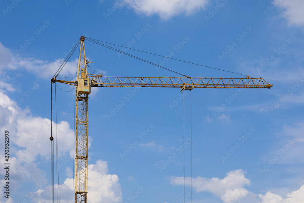 Industrial construction building crane against blue cloudy sky