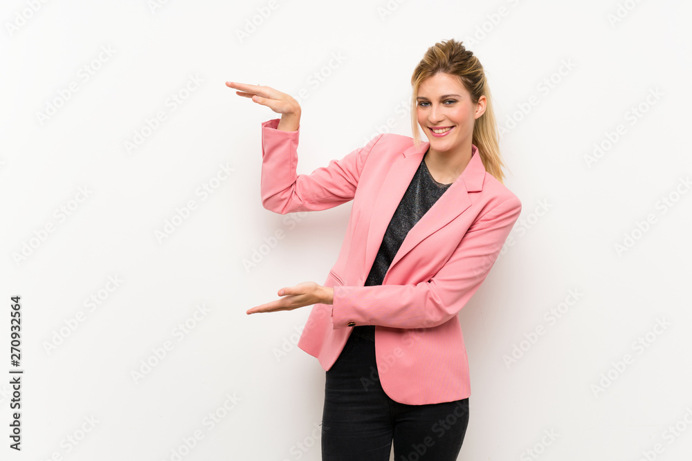 Young blonde woman with pink suit holding copyspace to insert an ad