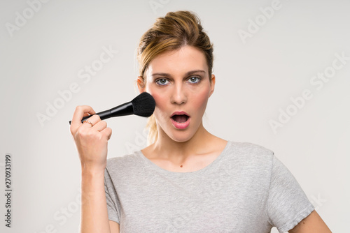 Young blonde woman with makeup brush