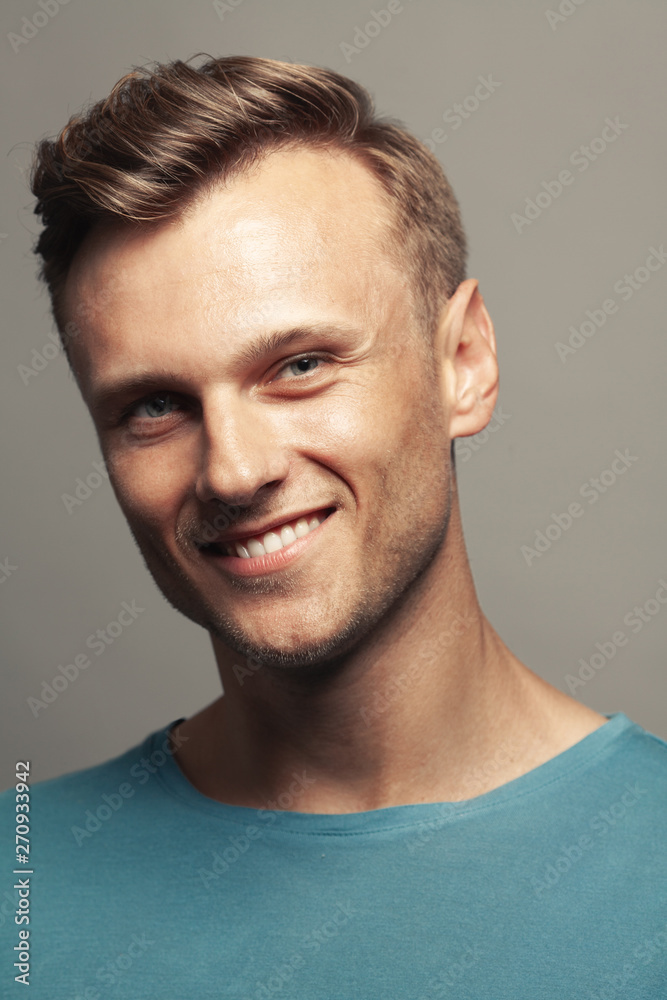 Fototapeta premium Fabulous at any age. Portrait of handsome 30-year-old man with blue eyes standing over gray background. Close up. Classic style. Shiny white smile. Headshot. Studio shot