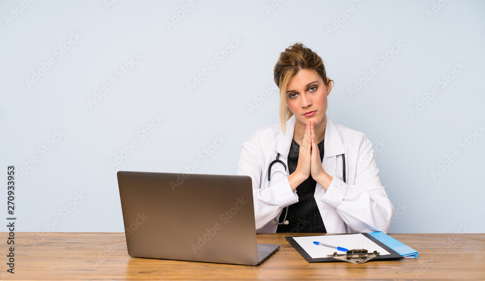 Blonde doctor woman keeps palm together. Person asks for something Blonde doctor woman keeps palm together. Person asks for something
